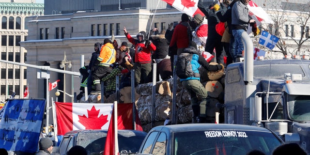FOTO FILE: Demonstran berdiri di atas trailer membawa kayu gelondongan ketika pengemudi truk dan pendukung berpartisipasi dalam konvoi untuk memprotes mandat untuk vaksin virus corona (COVID-19) untuk pengemudi truk lintas batas di Ottawa, Ontario, Kanada, 29 Januari 2022. REUTERS / PATRICK DOYLE / FILE Gambar