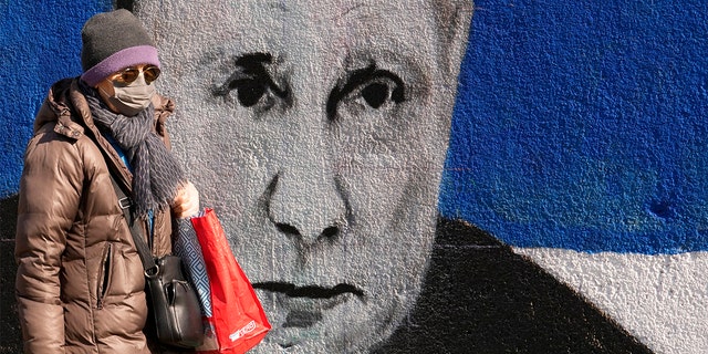 Seorang wanita berjalan melewati mural yang menggambarkan Presiden Rusia Vladimir Putin di Beograd, Serbia, Sabtu, 12 Maret 2022. 