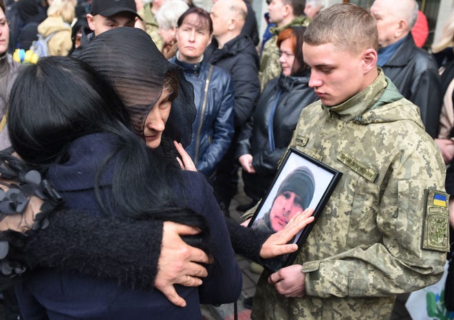 Kerabat memeluk pemakaman tentara Ukraina Theodore Osadchy di pemakaman Lychakiv di Lviv, Ukraina barat, pada 29 Maret 2022.