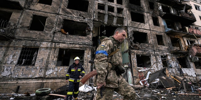 Tentara Ukraina dan petugas pemadam kebakaran memeriksa bangunan yang hancur setelah serangan bom di Kyiv, Ukraina, Senin, 14 Maret 2022. 