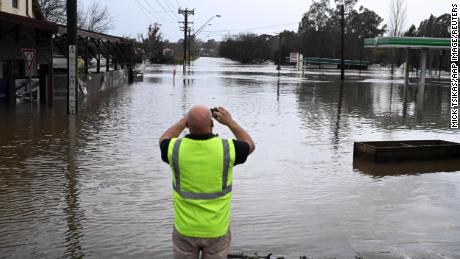 Seorang warga mengambil foto jalan yang terendam banjir di Camden di barat daya Sydney, Minggu, 3 Juli 2022.