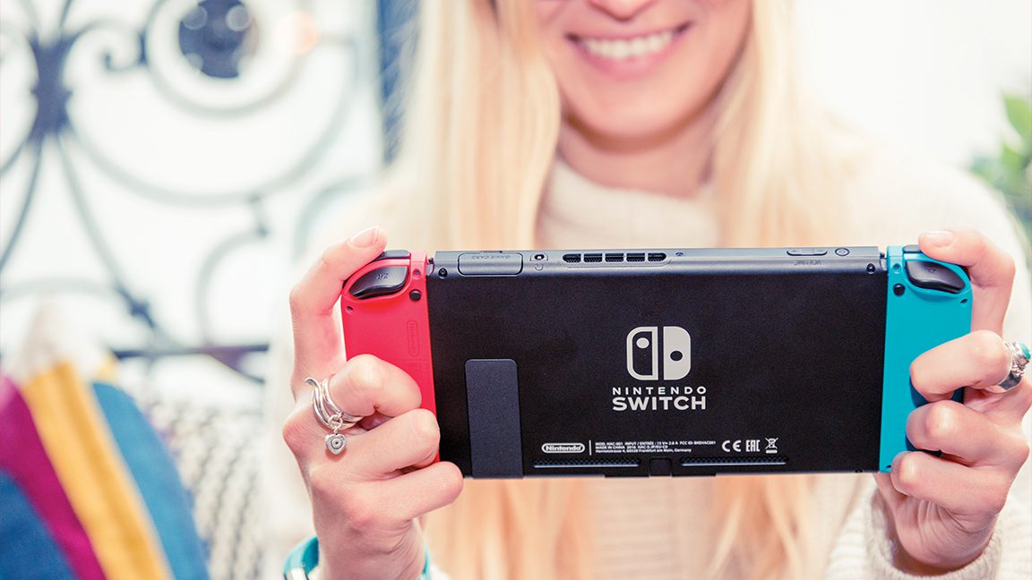 Gambar seorang wanita muda memainkan konsol game Nintendo Switch