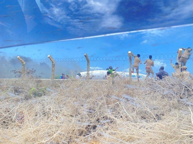 Komando Brigade Daneb Somalia memanjat pagar untuk mencapai pesawat Juba Air yang mendarat pada 18 Juli 2022 di Bandara Internasional Mogadishu, Mogadishu, Somalia.  Tiga tentara dari Brigade Bantuan Keamanan ke-2 dari Fort Bragg membantu responden pertama merawat 16 penumpang yang terluka.