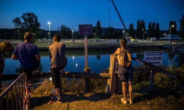 Penonton dan penduduk setempat melihat tim penyelamat saat mereka mengangkut paus beluga yang hilang yang terperangkap di Sungai Seine.