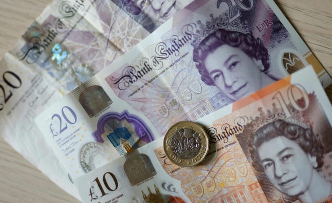 File foto yang diambil pada 22 April 2022 menunjukkan uang kertas pound Inggris dan koin yang dipajang di atas meja di London.  Uang kertas pada akhirnya akan berubah setelah kematian Ratu Elizabeth II.