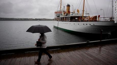 Seorang pejalan kaki melindungi diri dengan payung saat berjalan di sepanjang tepi pantai Halifax yang diguyur hujan sebelum Badai Fiona mendarat di Halifax, Jumat, 23 September 2022.