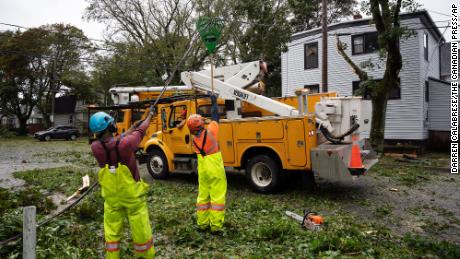 Pekerja mengangkat kabel yang dipotong untuk memungkinkan mesin mencapai pohon gugur di Halifax, Nova Scotia, pada hari Sabtu.