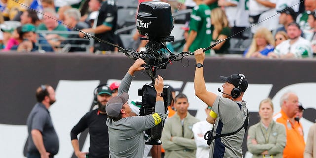 Pekerja memperbaiki kamera jarak jauh selama penundaan selama paruh kedua pertandingan sepak bola NFL antara New York Jets dan Buffalo Bills, Minggu, 6 November 2022, di East Rutherford, New Jersey.