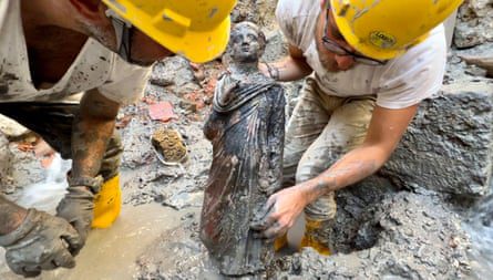 Dua arkeolog memegang patung anak laki-laki.