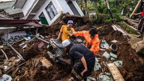 Warga menyelamatkan barang-barang dari rumah yang rusak pascagempa bermagnitudo 5,6 di Cianjur pada 22 November 2022. 