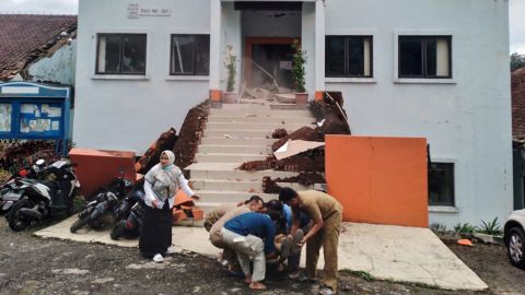 Petugas kota di Cianjur mengevakuasi seorang rekan yang terluka setelah gempa.
