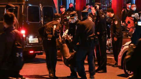 Polisi menahan seorang demonstran di Shanghai pada Minggu malam.